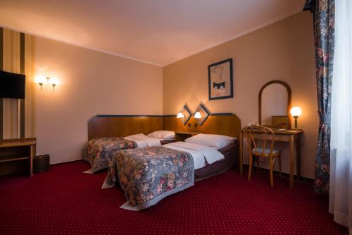 インドルジフーフ・フラデツにあるHotel Concertino Zlatá Husaのベッド2台とテーブルが備わるホテルルームです。