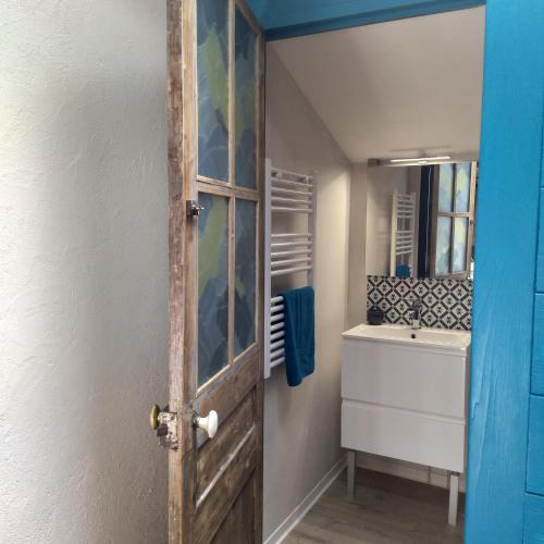 - une porte ouverte donnant sur une salle de bains avec lavabo dans l'établissement La Mezzabulle, à Chapaize