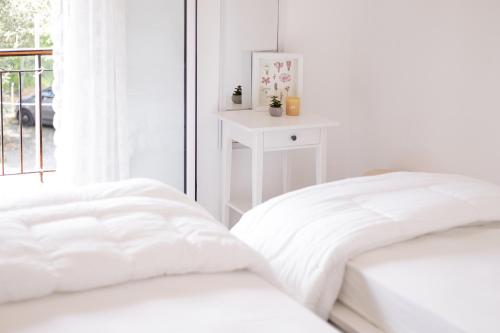 two white beds in a white room with a window at The Island Life Apartments by Konnect, Ipsos Beach in Ýpsos