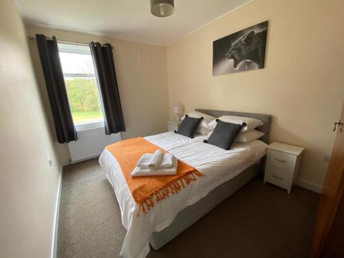 a bedroom with a bed with an orange blanket and a window at Machermore Castle in Newton Stewart