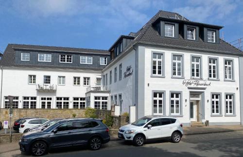 zwei Autos auf einem Parkplatz vor einem Gebäude geparkt in der Unterkunft Privathotel Riesenbeck in Riesenbeck