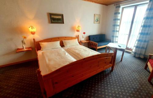 a bedroom with a wooden bed and a living room at Pension Berg&Bleibe Wertach in Wertach
