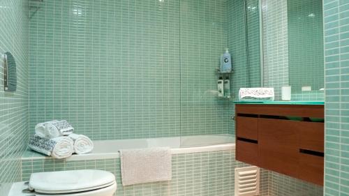 La salle de bains est pourvue de carrelage vert, de toilettes et d'une baignoire. dans l'établissement CASA AURA, à Olhão