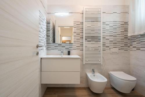 a white bathroom with a sink and a toilet at Palm Beach Jesolo in Lido di Jesolo