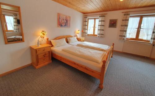 a bedroom with a bed and a nightstand and windows at Pension Berg&Bleibe Wertach in Wertach