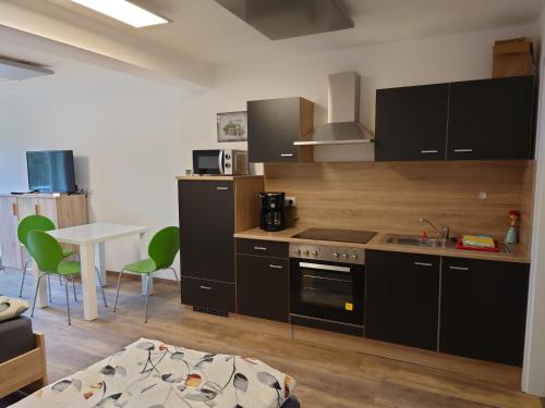 a kitchen with black appliances and a table and chairs at Ferienwohnungen Kay in Kirchaich