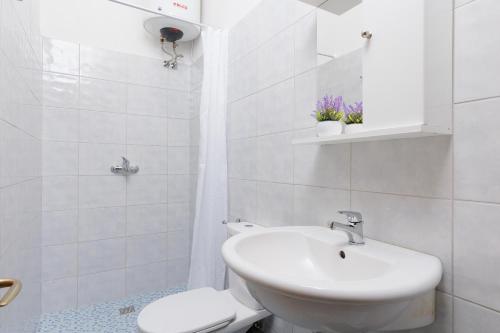 a white bathroom with a sink and a toilet at The Island Life Apartments by Konnect, Ipsos Beach in Ýpsos
