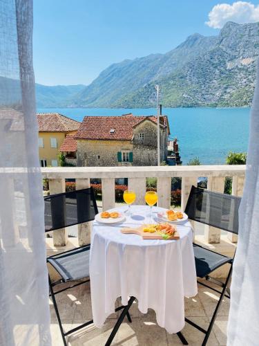 a table with two glasses of wine on a balcony at Villa Blanca in Risan