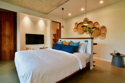 a bedroom with a large white bed with blue pillows at Coconut Lane Bangkok in Bangkok