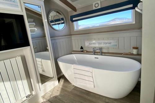 a large white tub in a bathroom with a window at St Ives Bay in Phillack