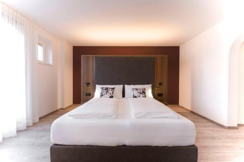 1 dormitorio con 1 cama blanca grande y 2 almohadas en Gran Tubla, en Ortisei