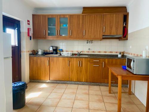 uma cozinha com armários de madeira e piso em azulejo em Pirata hostel Milfontes em Vila Nova de Milfontes
