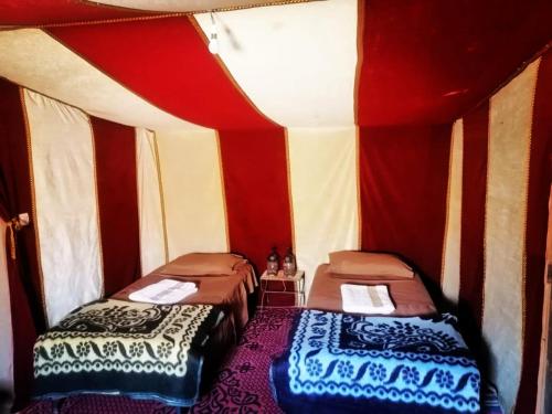 two beds in a room with red and white walls at Bivouac Le charme d'Aladdin in El Gouera