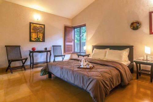 - une chambre avec un lit, 2 chaises et une table dans l'établissement Kay Villa by StayVista with Pool, Lawn, Gazebo, Hammoc & Stunning interiors, à Alibaug