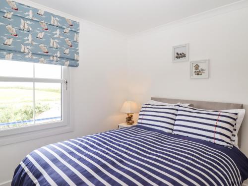 a bedroom with a bed with a blue and white striped bedspread at Azure in St Ives