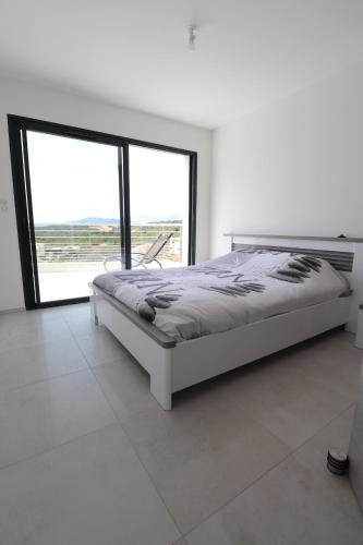 une chambre blanche avec un lit et une grande fenêtre dans l'établissement T3 Villas ACUM- Agosta plage - vue MER et Îles sanguinaires, à Porticcio