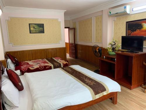 a bedroom with a bed and a desk and a television at Ngan Nga Bac Ha Hotel in Bắc Hà