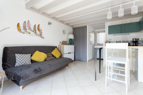 un salon avec un canapé noir et une cuisine dans l'établissement La maisonnette malouine, à Saint-Malo