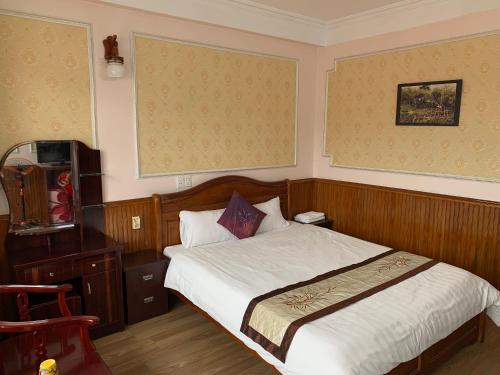 a bedroom with a bed and a desk and a television at Ngan Nga Bac Ha Hotel in Bắc Hà