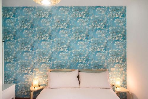 une chambre avec un mur floral bleu avec un lit dans l'établissement S255 - Sirolo, nuovo trilocale a due passi dal centro, à Sirolo