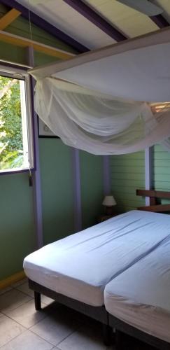 1 dormitorio con 1 cama blanca en una habitación con ventana en Gites Cabazat en Bouillante