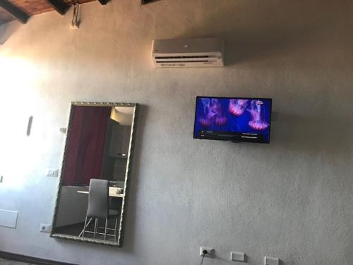 un televisor en una pared junto a un espejo en Monolocale Belvedere su Porto Rotondo en Cugnana