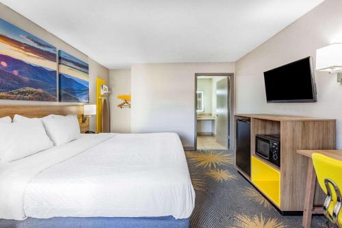 a hotel room with a bed and a flat screen tv at Days Inn by Wyndham Roanoke Hollins Near I-81 in Roanoke