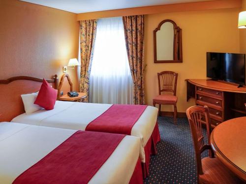 a hotel room with two beds and a table at Mercure Andorra in Andorra la Vella