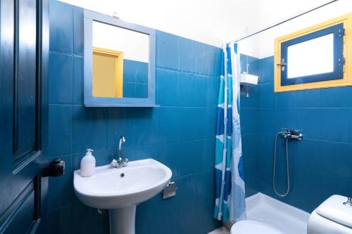 a blue bathroom with a sink and a shower at Afroditi Apartments in Makry Gialos