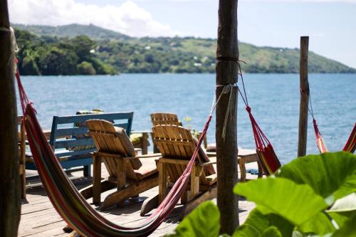 - deux chaises et un hamac sur un quai au bord de l'eau dans l'établissement Butterfly Space- A Non-Profit Eco-Lodge, à Nkhata Bay