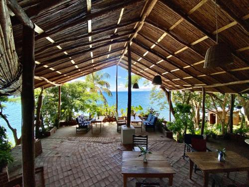 a patio with tables and chairs and a view of the ocean at Butterfly Space- A Non-Profit Eco-Lodge in Nkhata Bay