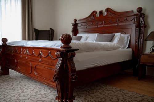 a bedroom with a wooden bed with white pillows at Palais Kneissl in Burgau