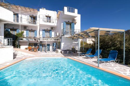 a swimming pool with chairs and umbrellas in front of a building at Afroditi Apartments in Makry Gialos