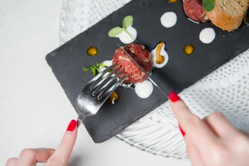 a person holding a fork with a dessert on a plate at Historic Hotel Ristorante La Stua in Cavalese