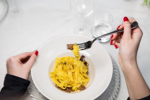 a person eating a bowl of pasta with a fork at Historic Hotel Ristorante La Stua in Cavalese