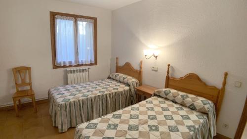 a room with two beds and a chair and a window at C12 - Apartamento Casa Llorgodo 3 - Villmor in Cerler
