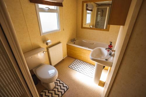 a bathroom with a toilet and a sink and a tub at 2 bedroom caravan in Lochlands leisure park in Forfar