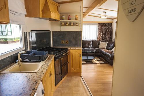 a kitchen with a sink and a stove top oven at Lochlands 2br family caravan - pets-play park in Forfar