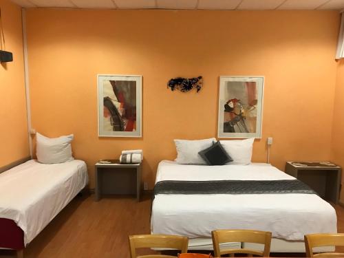 um quarto com duas camas e duas fotografias na parede em PensionLien em Köthen