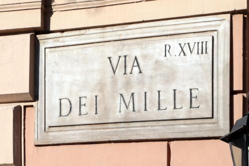 a sign on a building that reads va del millille at Hotel Dei Mille in Rome