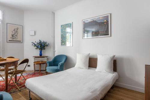 ein Schlafzimmer mit einem Bett und einem Tisch und Stühlen in der Unterkunft Veeve - Almond Blossom in Paris