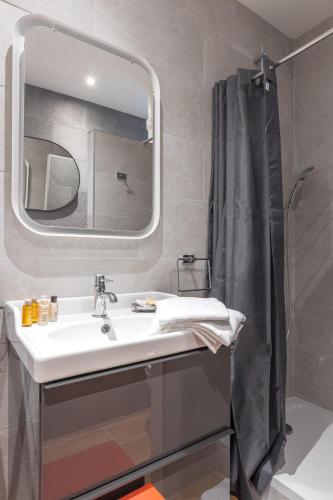 une salle de bain avec un lavabo et un miroir dans l'établissement Veeve - Almond Blossom, à Paris