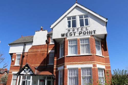 a white building with a sign on the front of it at West Point Hotel Bed and Breakfast in Colwyn Bay