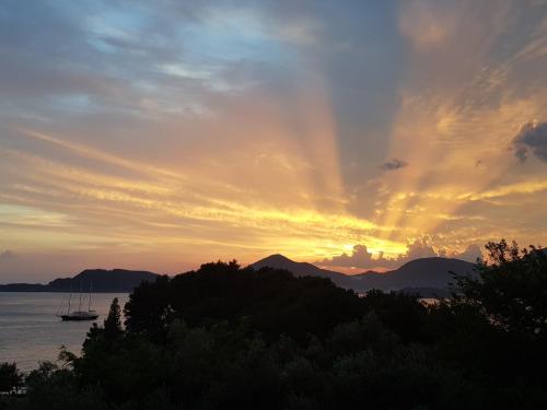 a sunset with a boat in the water at Vila Horizont in Sveti Stefan