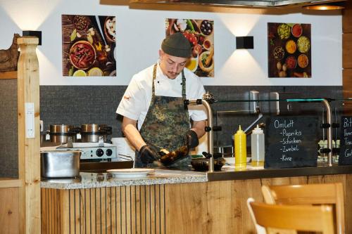 a man cooking in a kitchen preparing food at Ruperti - Gästehaus in Ainring