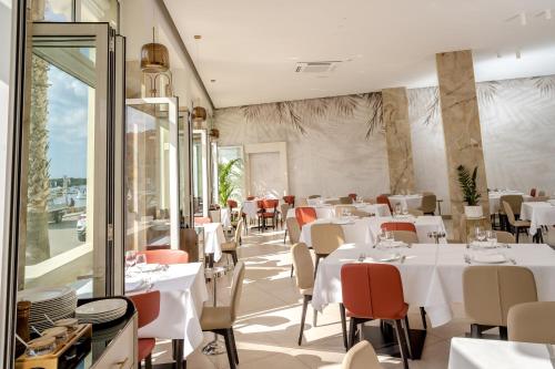 a restaurant with white tables and red chairs at Hotel Falli in Porto Cesareo