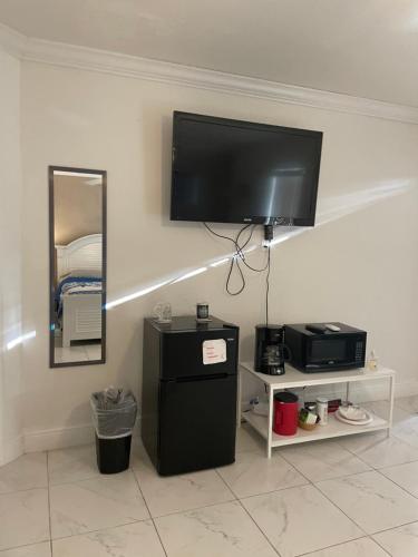 een flatscreen-tv aan een muur met een koelkast bij Blue Sky in Fort Myers