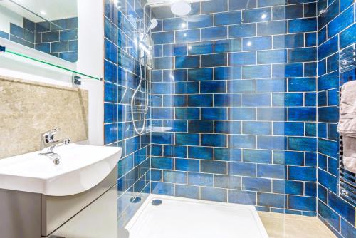 a blue tiled bathroom with a sink and a toilet at Rockpool - Bude in Bude