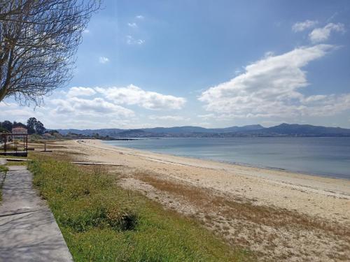 a beach with a bench and the ocean on a sunny day at APARTAMENTO A CASIÑA in Cangas de Morrazo