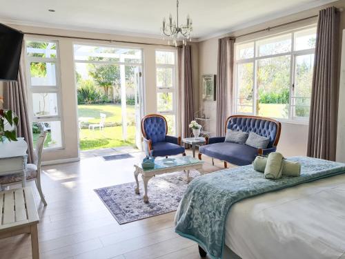 a bedroom with a bed and two blue chairs at Cherry Berry Lodge in George